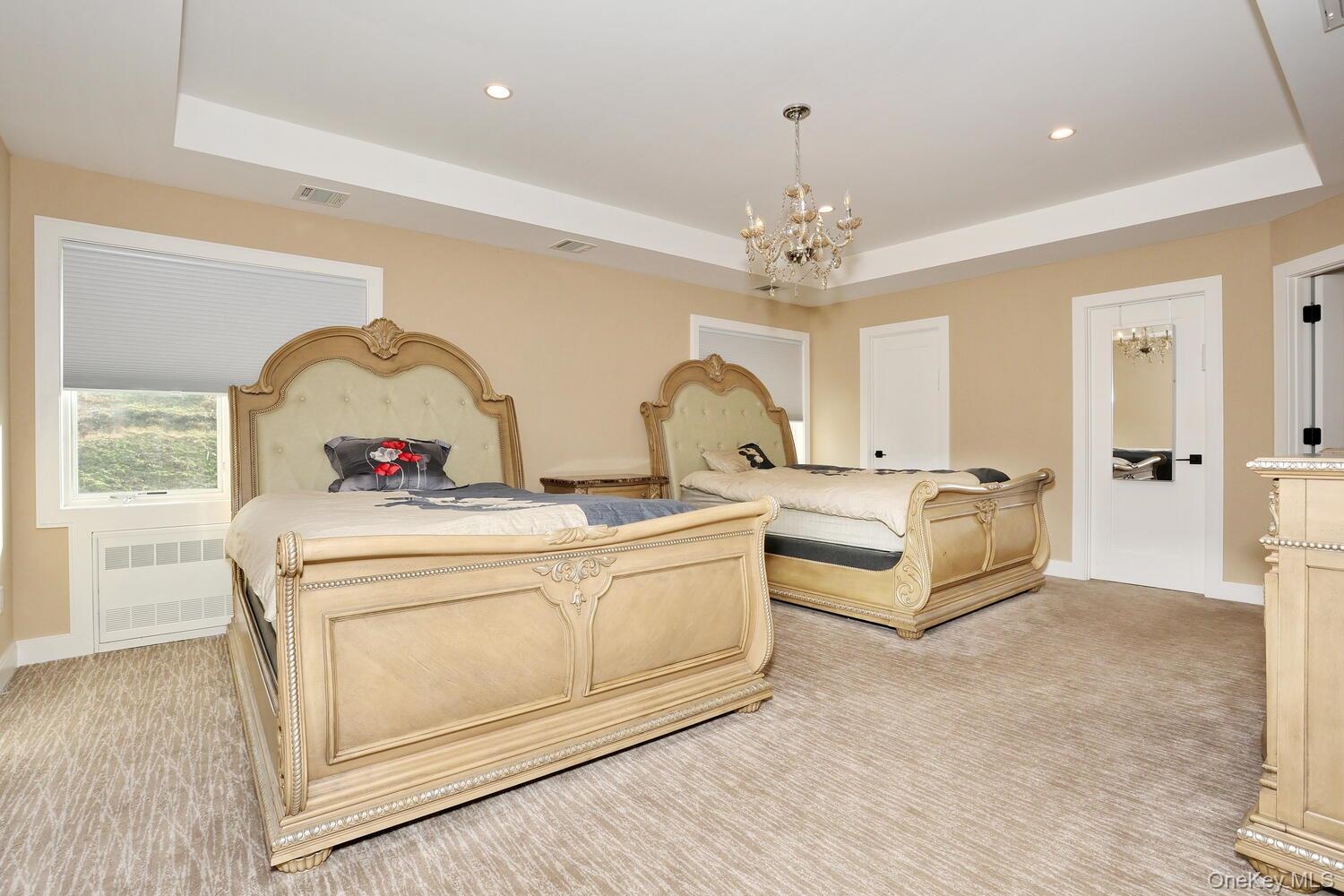 Bedroom featuring a raised ceiling, a chandelier, recessed lighting, and radiator heating unit