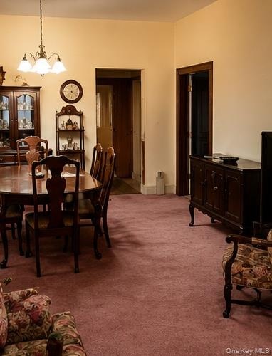 Dining area featuring a classic chandelier, warm neutral wall tones, and plush carpeting throughout