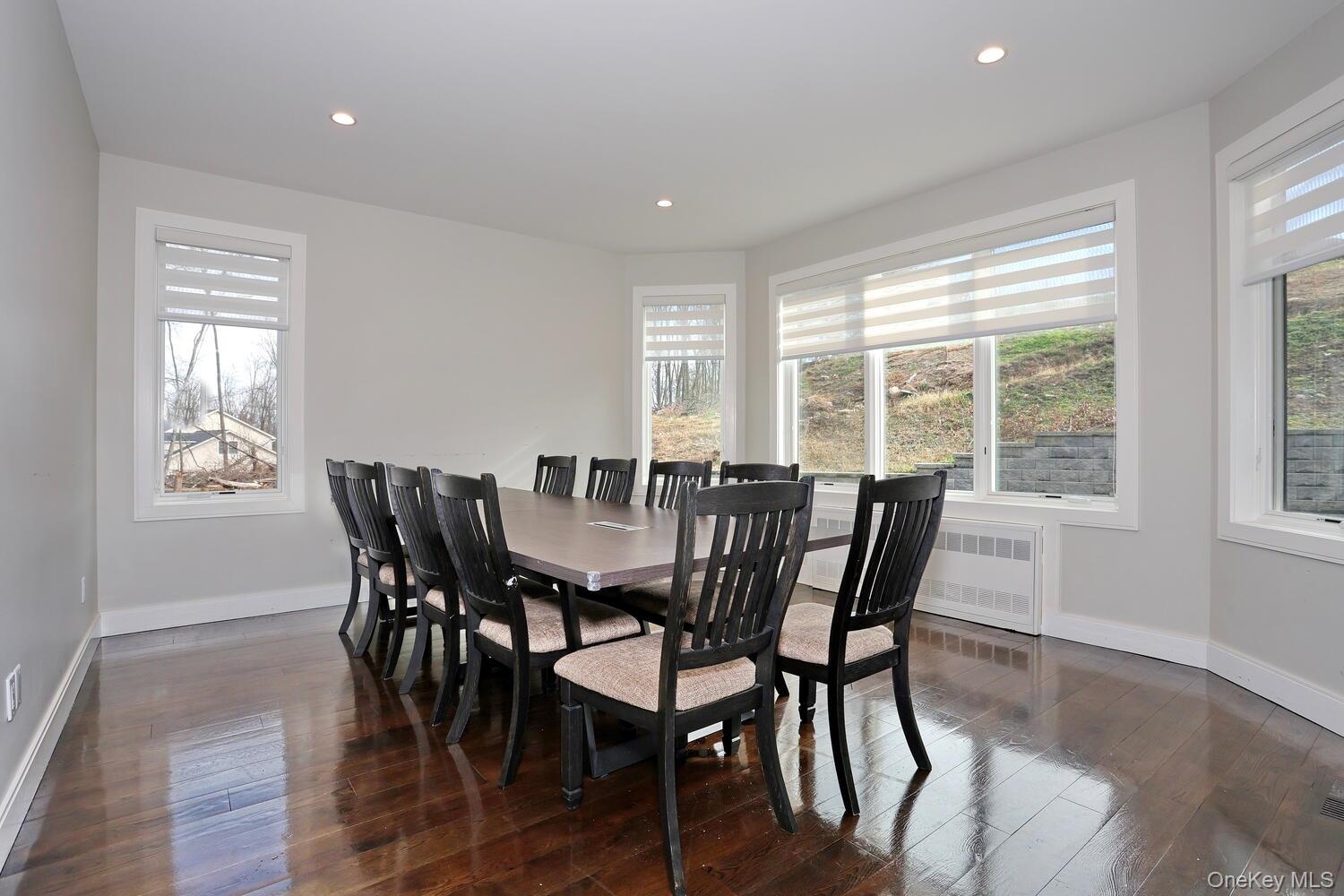 Dining space featuring dark wood-type flooring, recessed lighting, and radiator heating unit