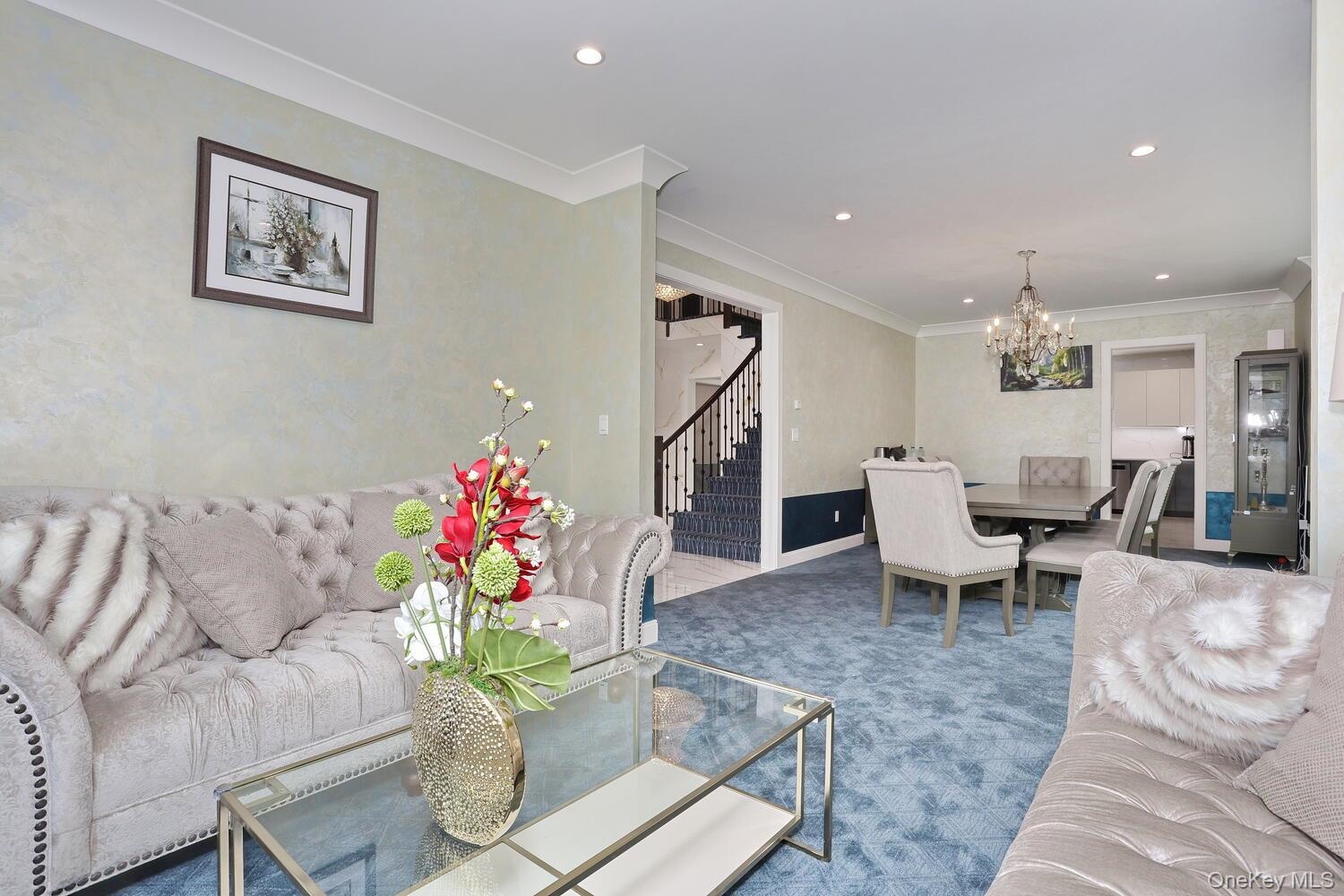 Living room with stairs, a chandelier, crown molding, recessed lighting, and carpet floors