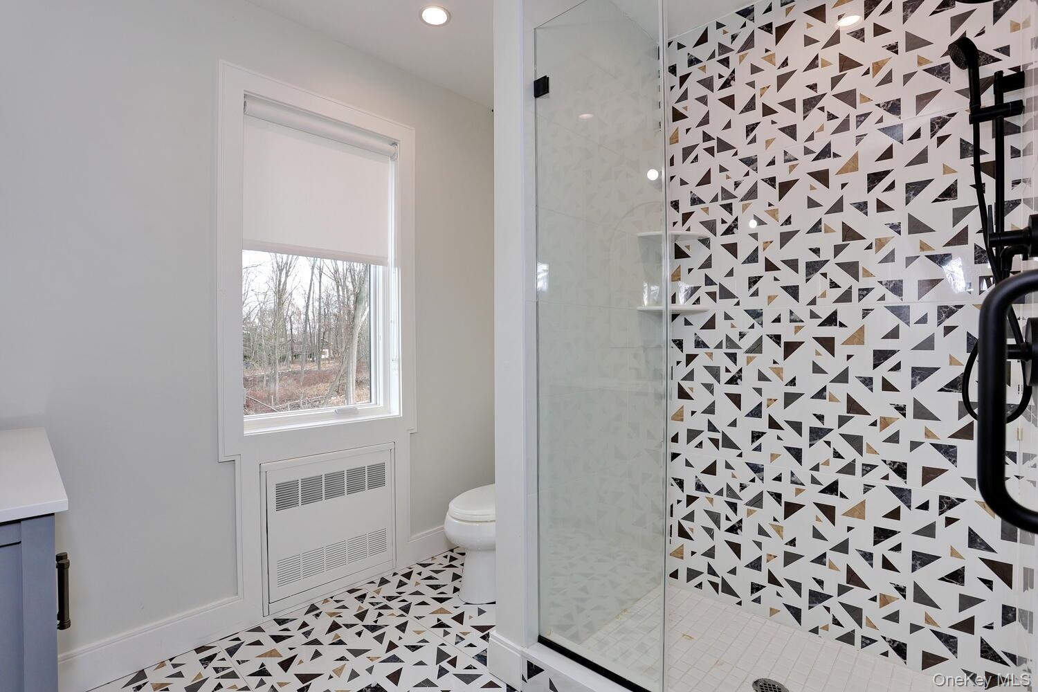 Full bath featuring vanity, a shower stall, and radiator heating unit