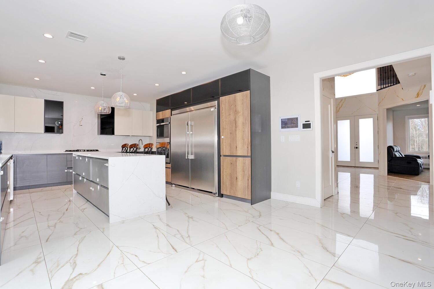 Kitchen featuring hanging light fixtures, modern cabinets, appliances with stainless steel finishes, a kitchen island, and gray cabinetry