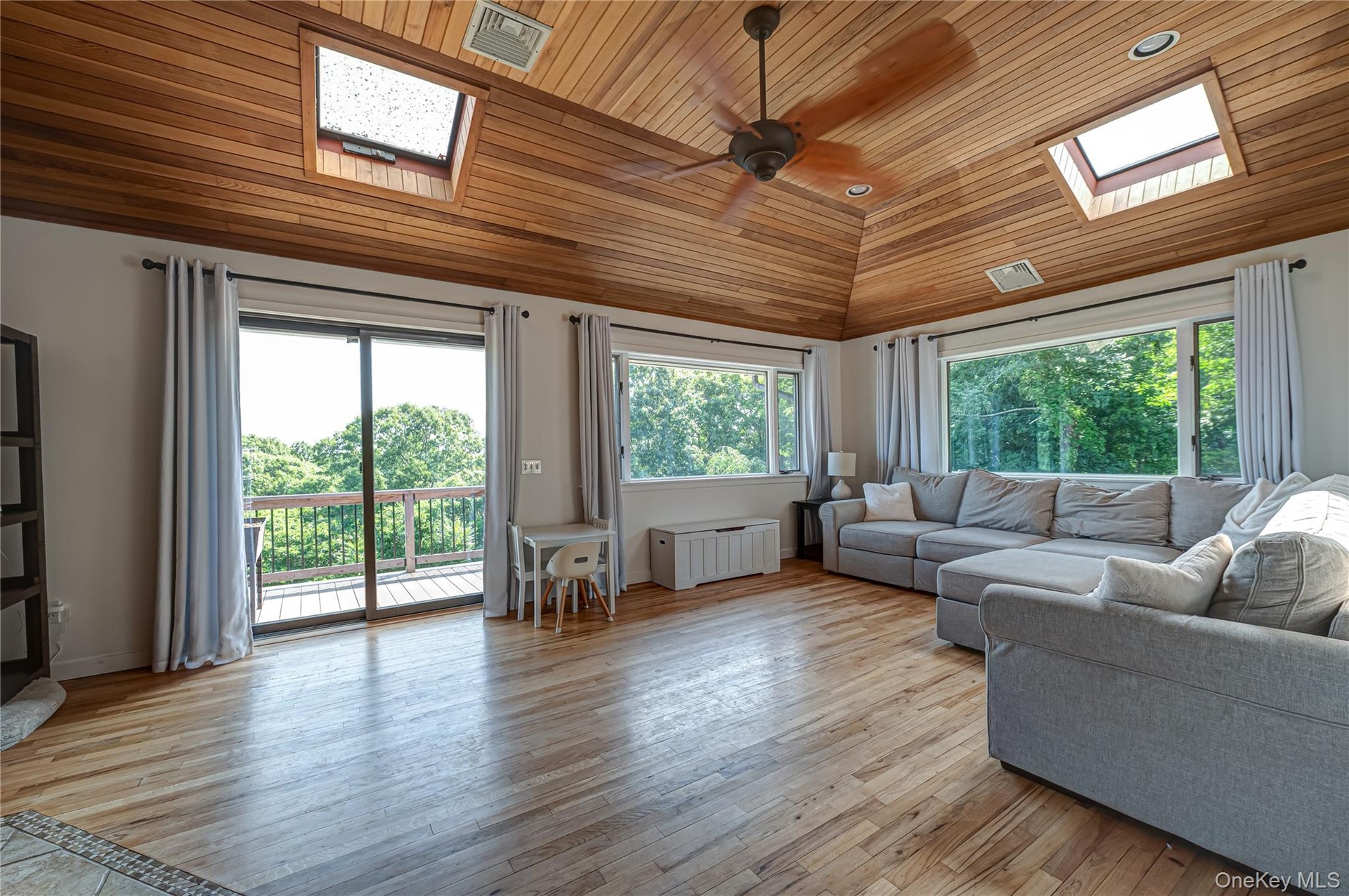 Huge Den with sliders to 2nd side deck overlooking natural 1/2 acre.  skylights & natural wood flooring