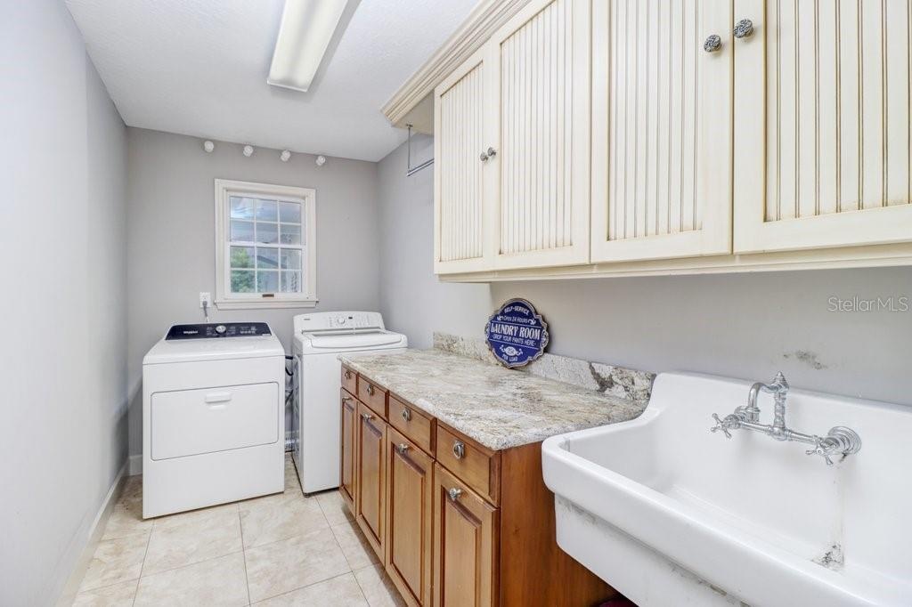 Oversized laundry room with built in custom cabinets, laundry tub, and washer and dryer included.
