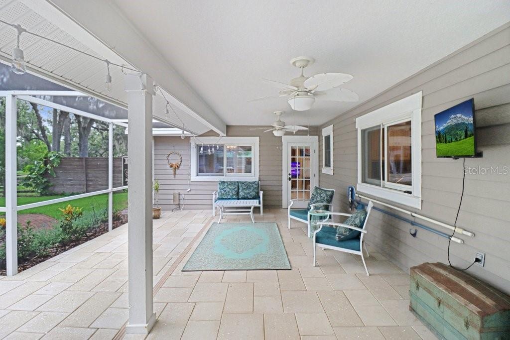 Relaxing patio area under roof with ceiling fans, perfect for parties and barbeques.