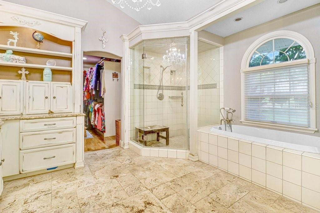 Large walk in steam shower with custom tile and shampoo nooks. Doorway to master bedroom closet.