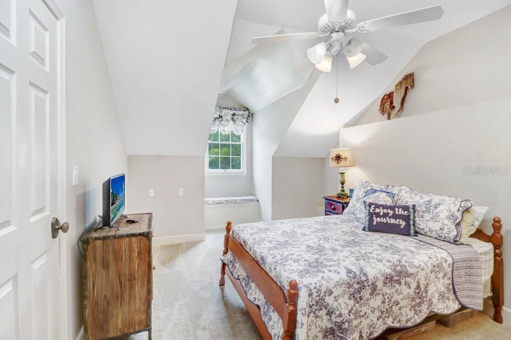 Large oversized guest room with window seat that has storage and walk in closet with vaulted ceilings.