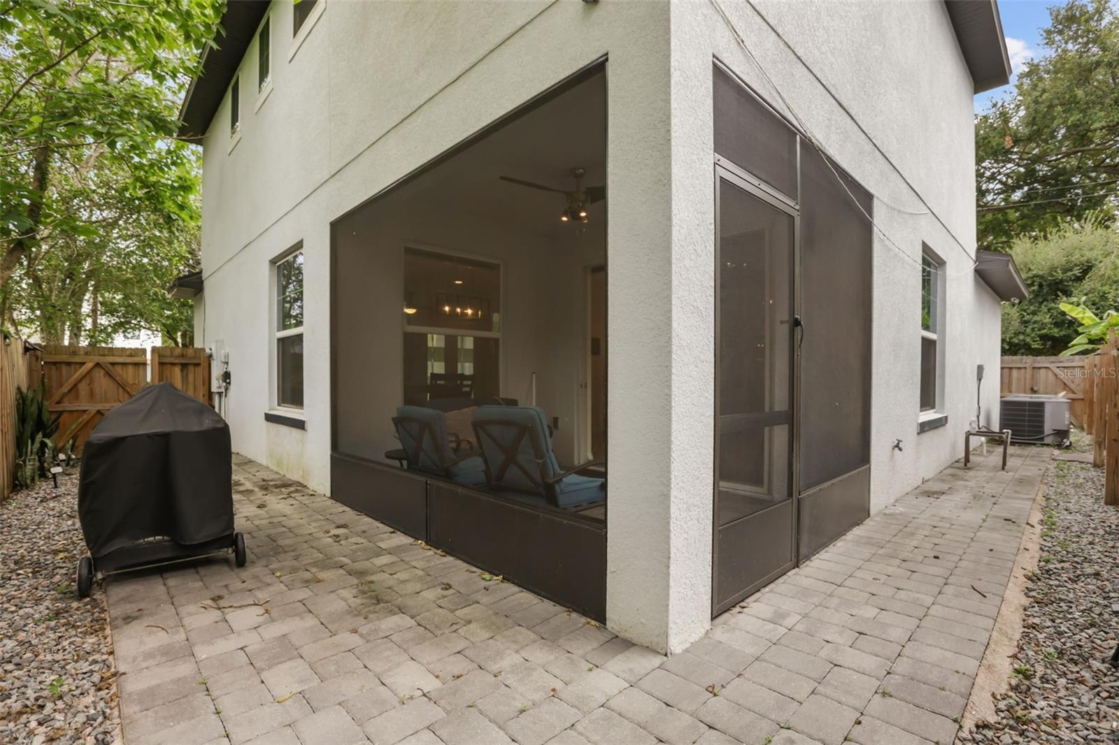 Exterior view showcasing the screened lanai, paver patio, and low-maintenance outdoor living space.