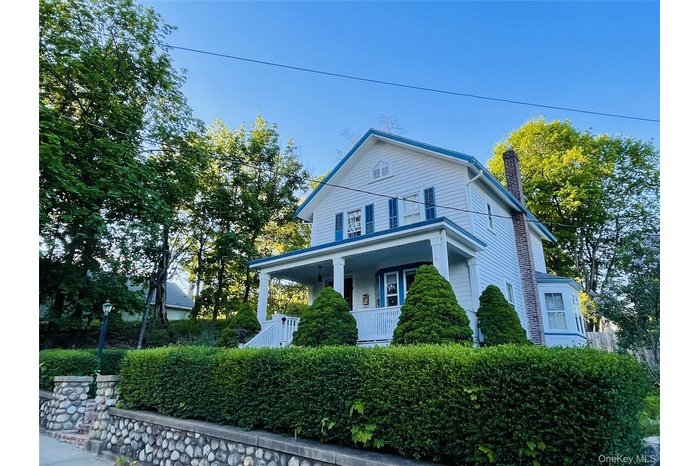 View of front of house with covered porch and stone wall