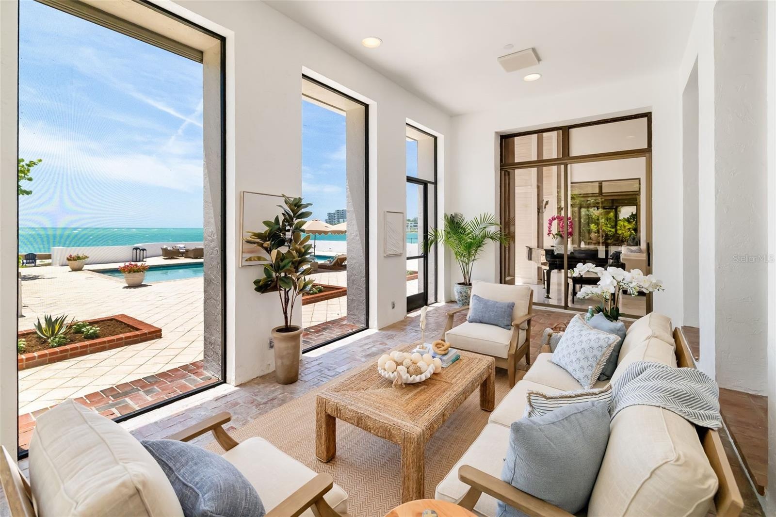 The covered and screened terrace off the formal living as well as the gathering room.  What a view of the gorgeous water and the swimming pool!