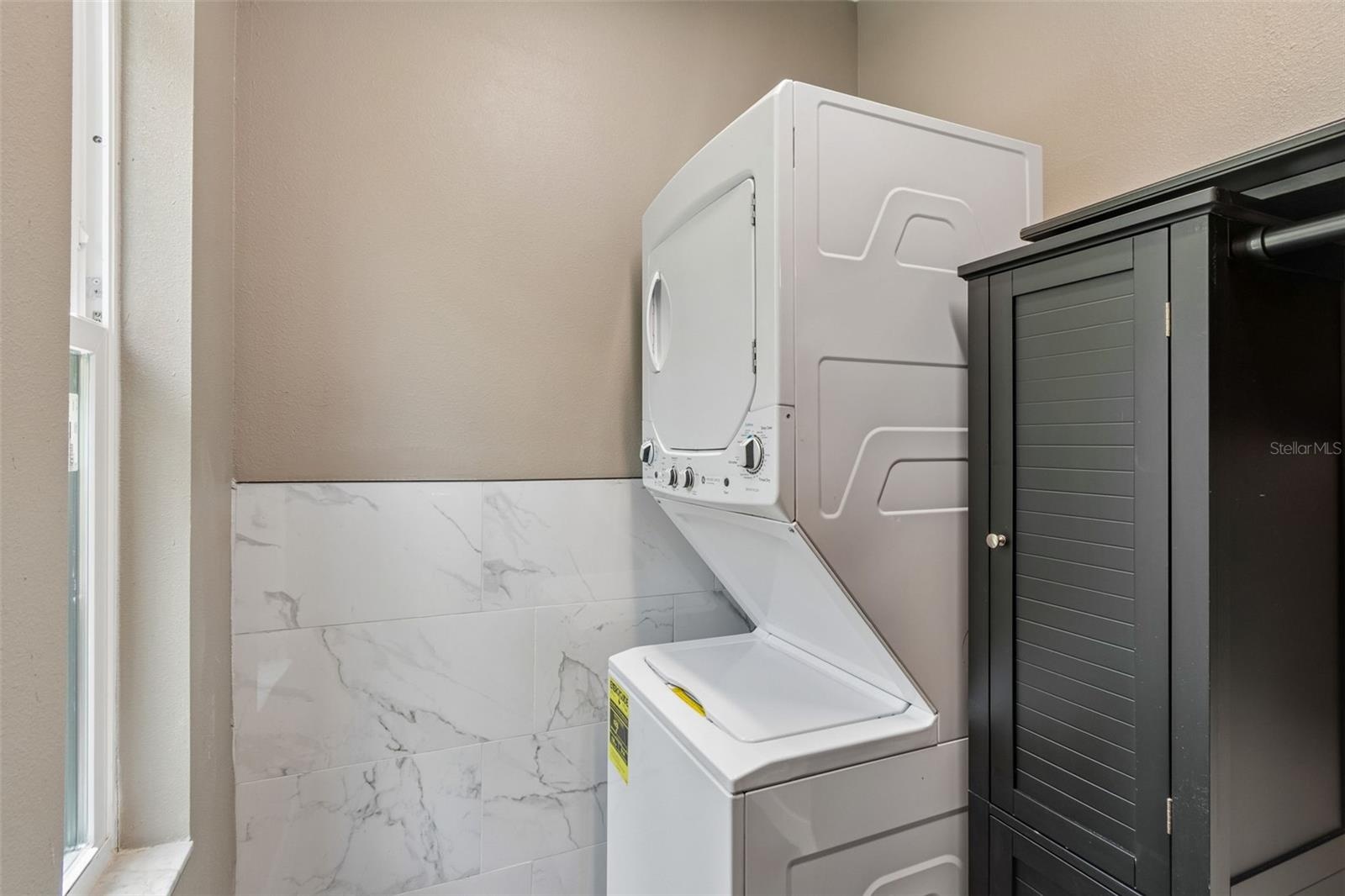 Stackable washer & dryer located next to the kitchen