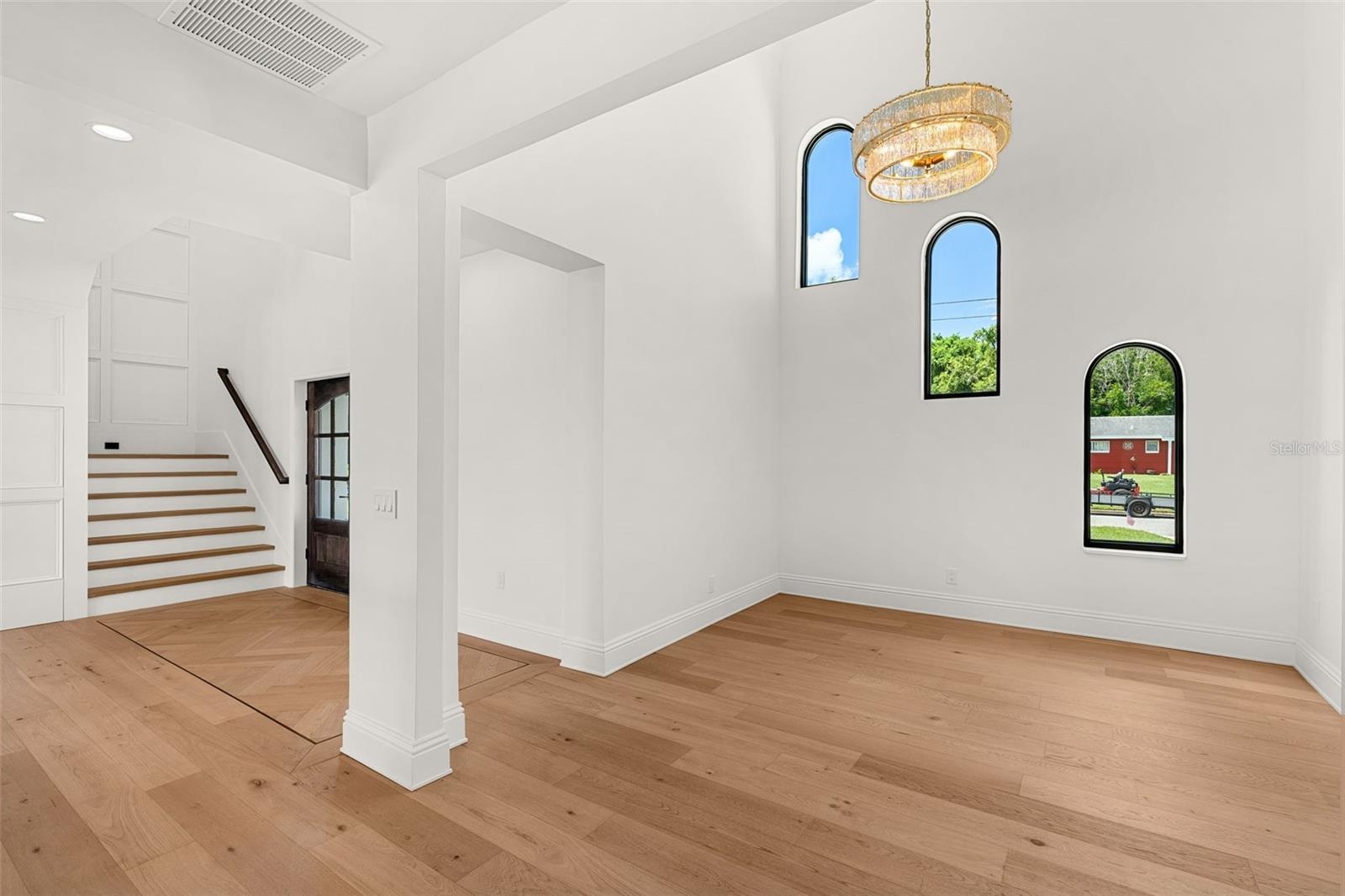 GRACIOUS DINING ROOM SHOWCASING SOARING ARCHED WINDOWS AND A DESIGNER CHANDELIER