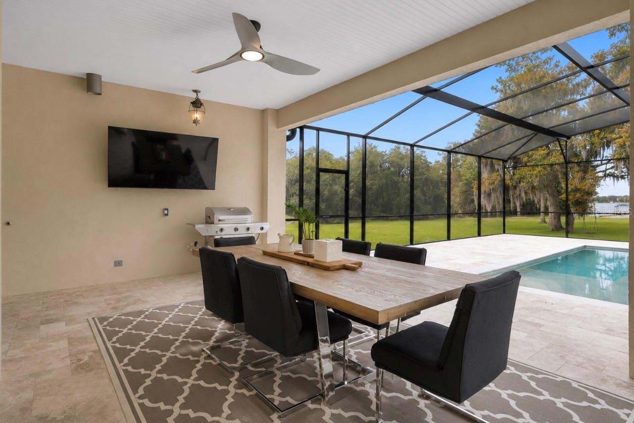 Oversized covered lanai designed for year-round outdoor living, dining and entertaining with peaceful water front views. Color of area rug has been vi
