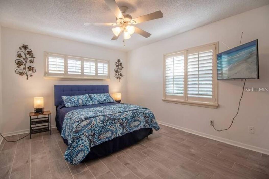 Master with queen bed, tv, side tables with lamp, ceiling fan, window to the outside.