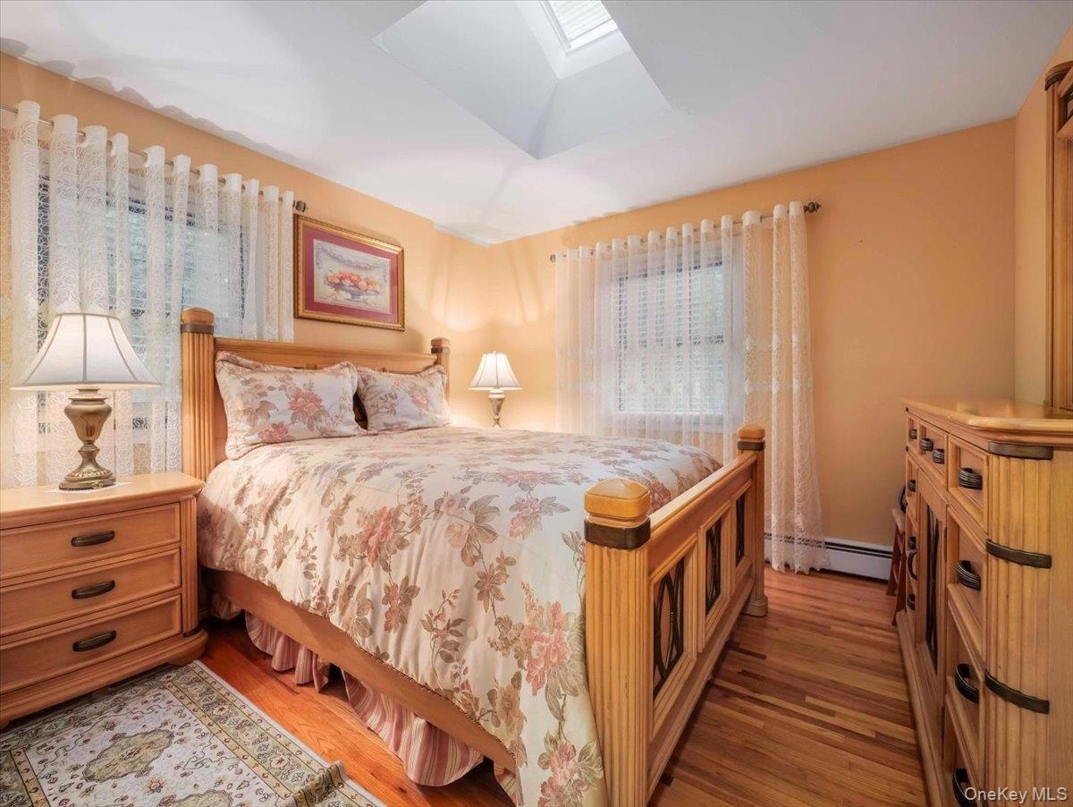 Bedroom featuring hardwood flooring, a skylight, and two windows with blinds