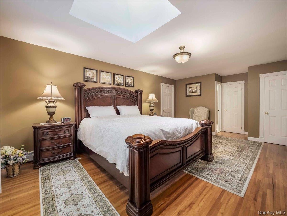 Bedroom featuring wood-finish flooring, a ceiling-mounted light fixture, and a skylight