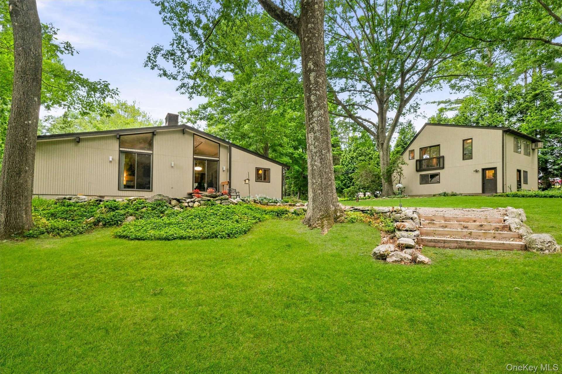 Expansive green lawn with mature trees and a rock-lined stone staircase