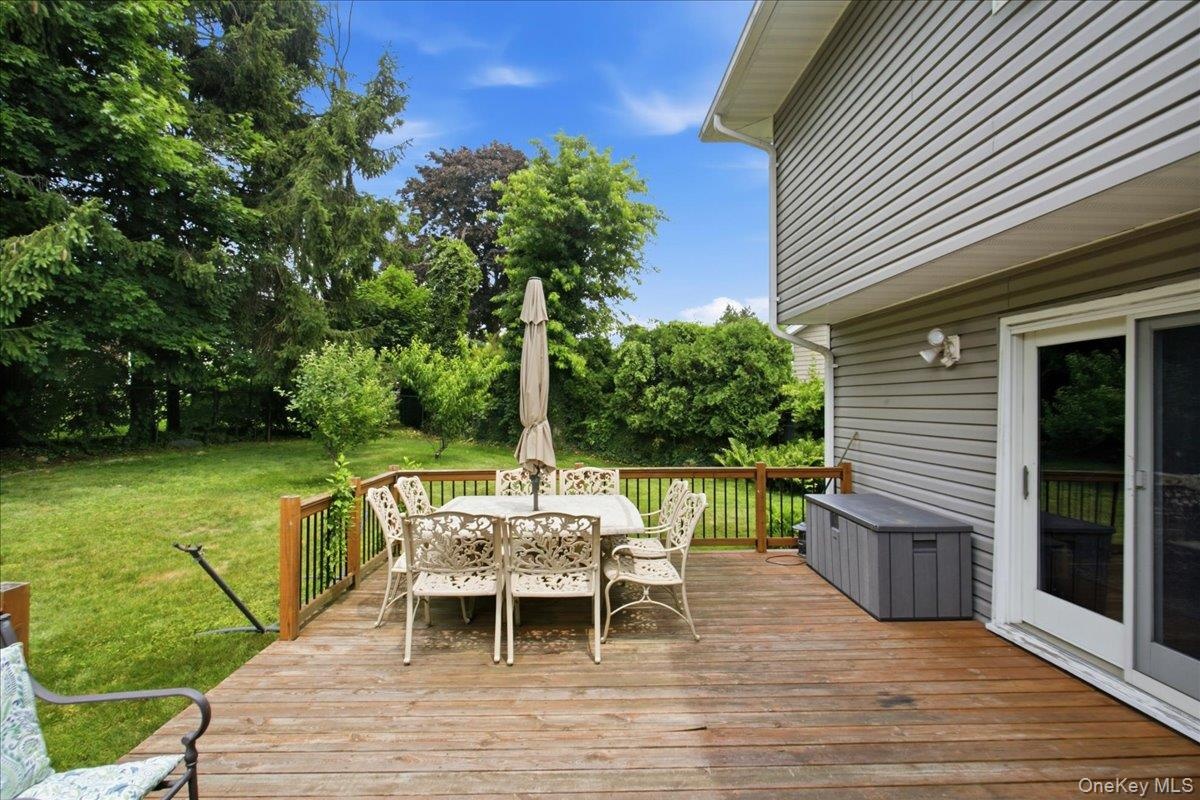 Spacious wood-finish deck bordered by a wooden railing overlooking a lush green lawn and mature trees