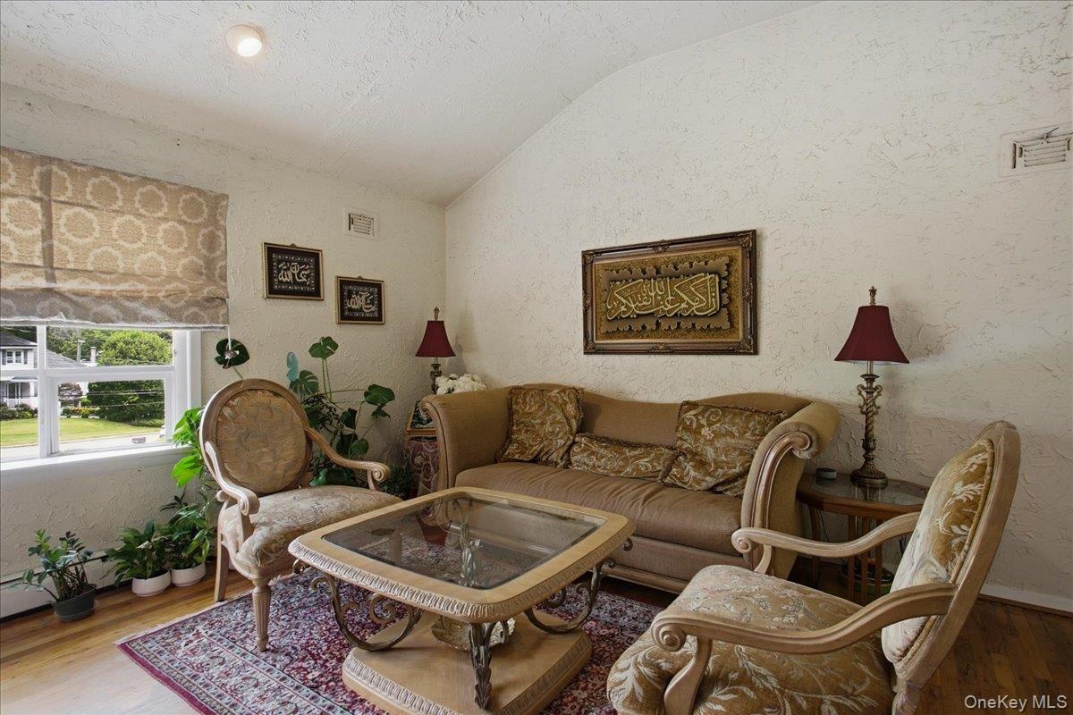 Living area featuring vaulted ceilings, textured wall finishes, and wood-finish flooring