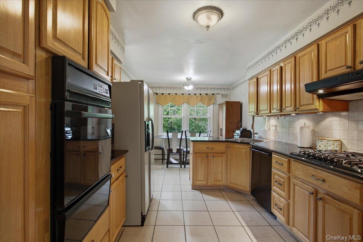 Kitchen featuring wood cabinetry, dark countertops, a built-in double oven, a gas cooktop, and tile flooring