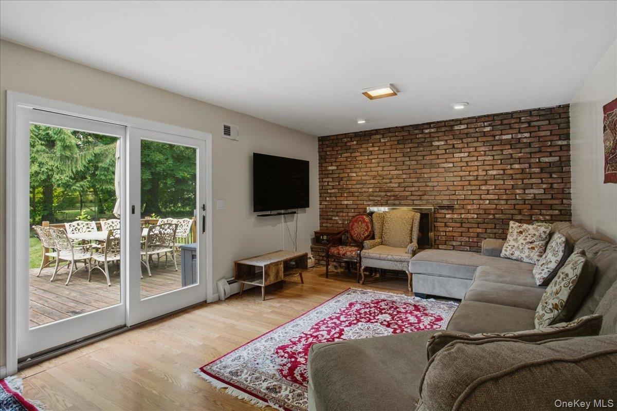 Living area featuring hardwood flooring, a brick accent wall, recessed lighting, and a sliding glass door providing access to an outdoor deck