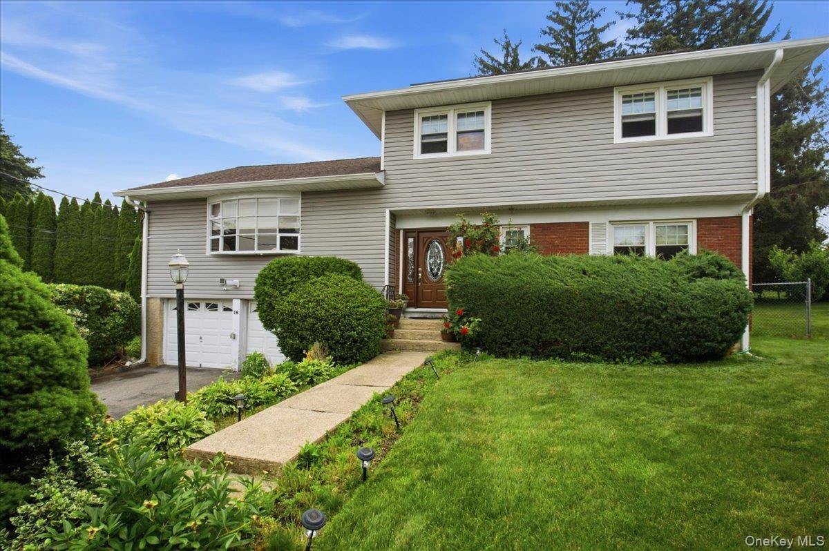 Split-level residence featuring gray siding and a brick facade