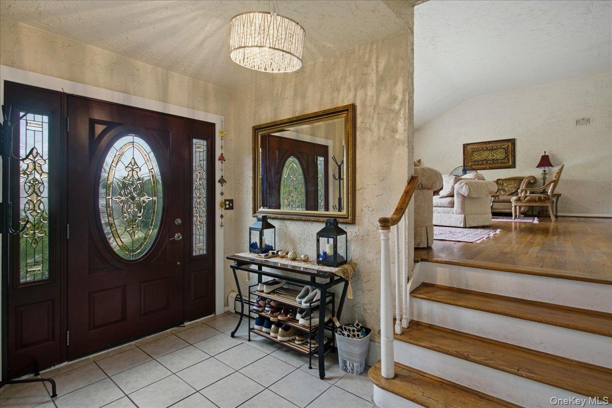 Entryway featuring a dark wood door with oval leaded glass, side panel windows, and a drum-style chandelier
