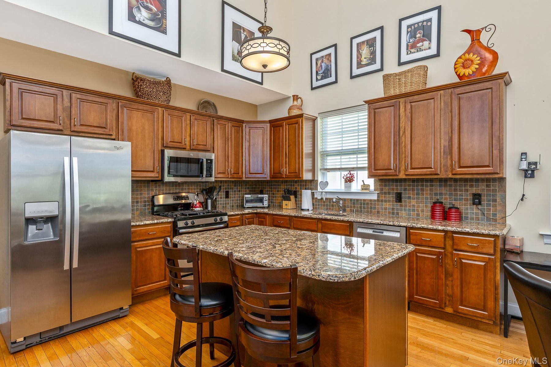 Kitchen featuring a central island with a granite countertop, wood cabinetry, stainless steel appliances