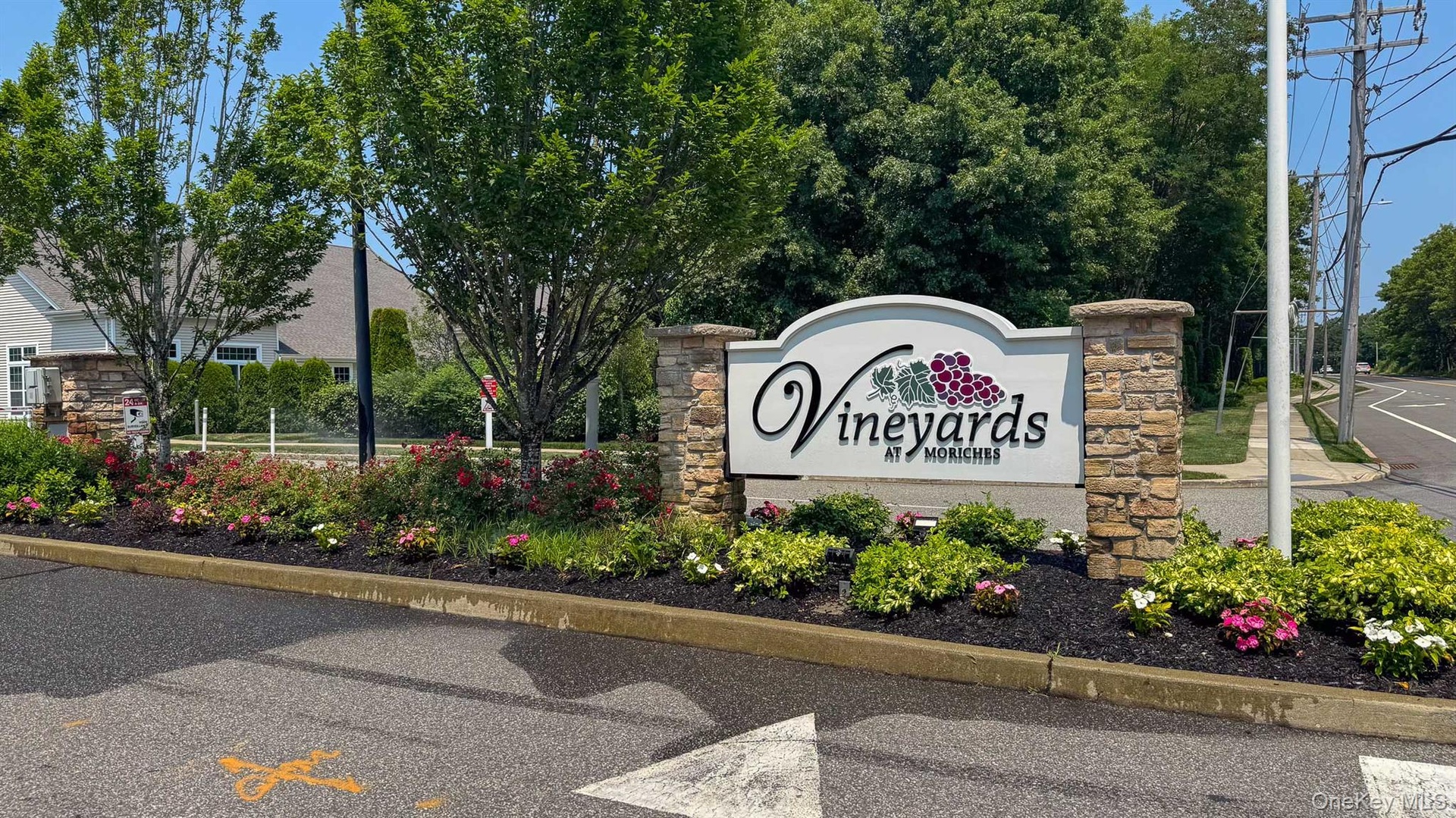 Beautiful Entrance sign featuring stone pillars and a white arched panel