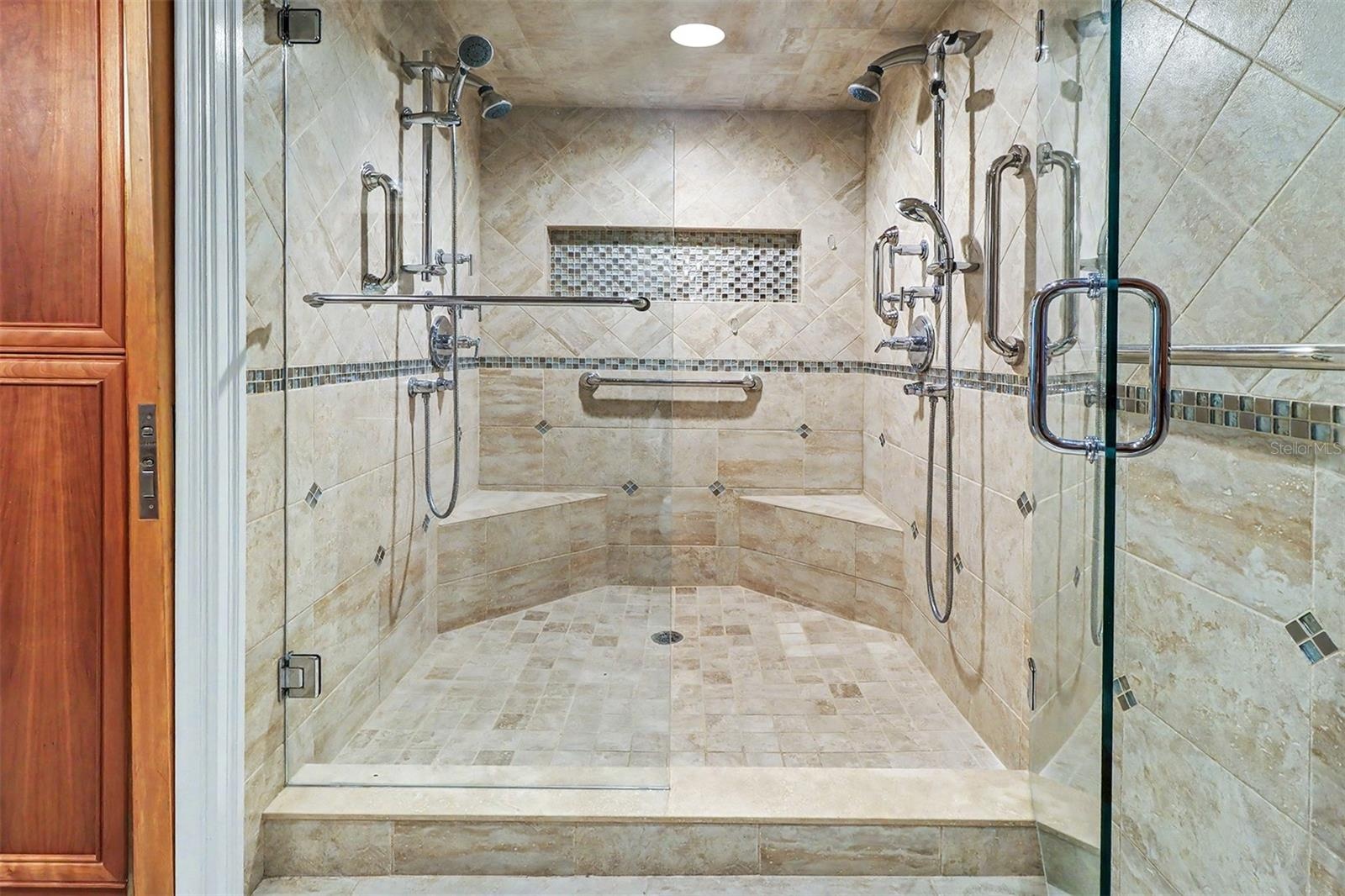 Indulge in the spa-inspired walk-in shower, beautifully finished with custom tile, built-in bench seating, dual shower heads, handheld sprayers, body 