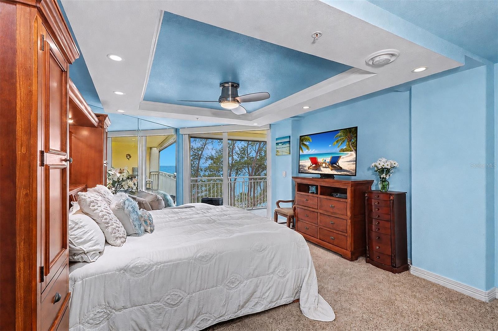 Primary Suite captures sweeping Gulf views and features direct balcony access, an adjustable split-top king bed, tray ceiling with ceiling fan, and TV
