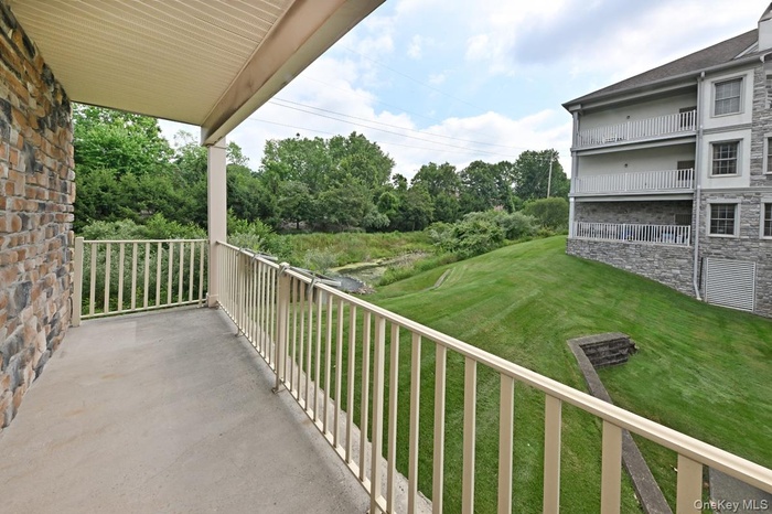 Extra large balcony with beautiful view of landscaping and pond with waterfall.