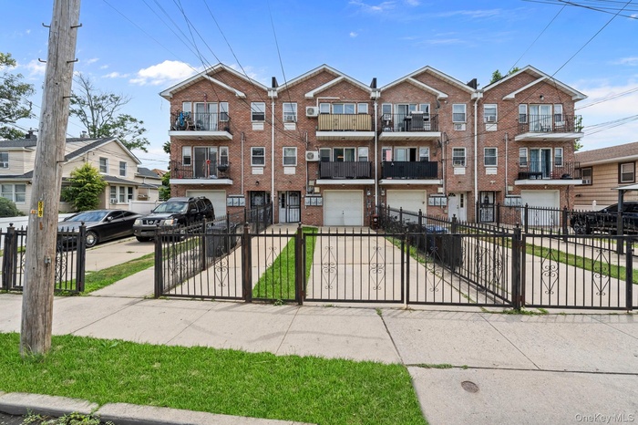 Brick facade townhouse featuring individual balconies, private driveways, and enclosed garage parking