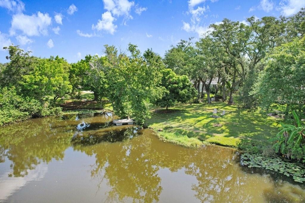 Drone view of spring fed lake, floating dock and backyard.