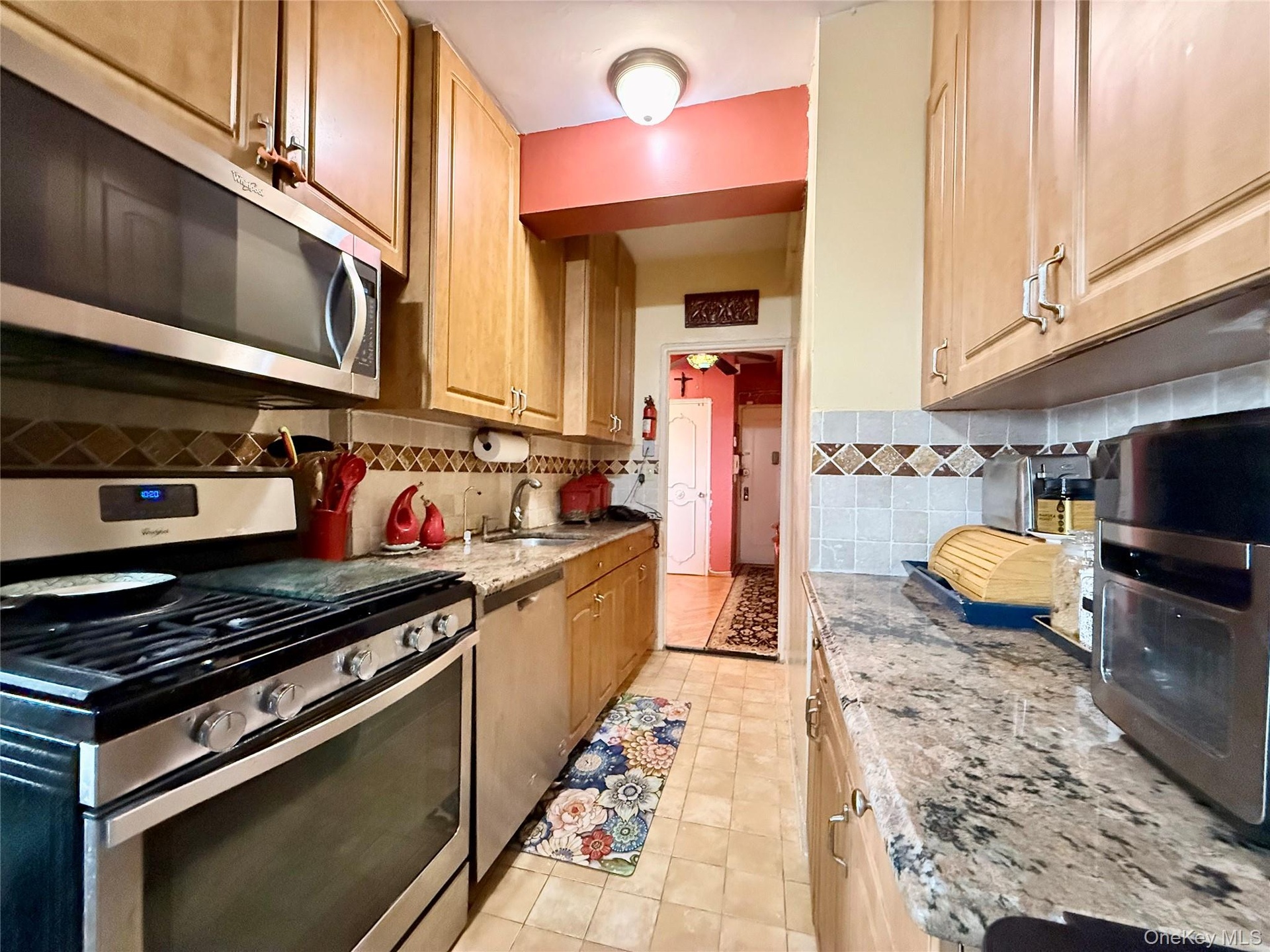 Well maintained kitchen, with light oak cabinets, granite countertop, tiled backsplash.