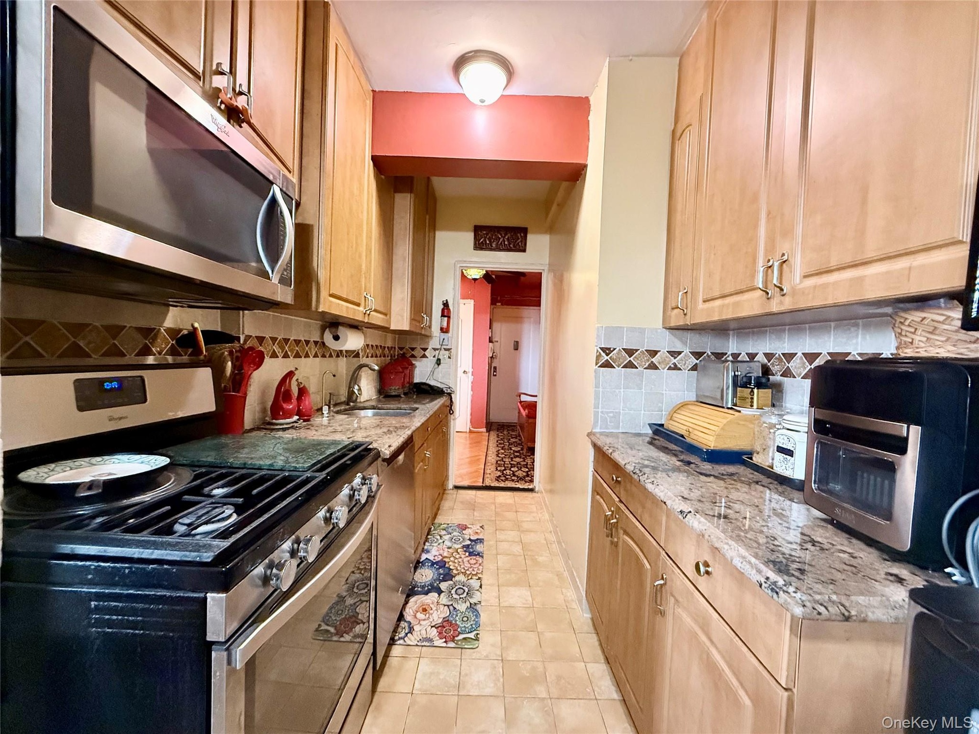 Well maintained kitchen, with light oak cabinets, granite countertop, tiled backsplash.