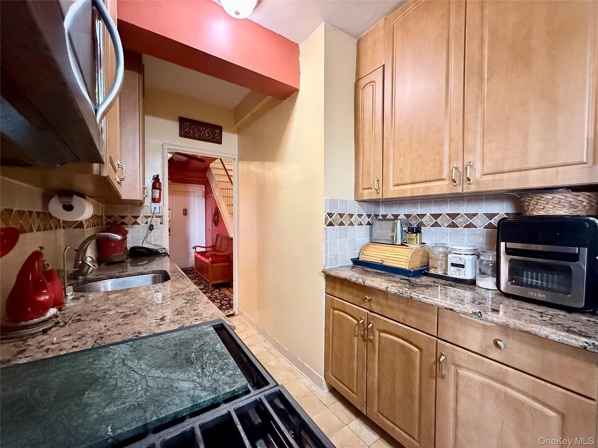 Well maintained kitchen, with light oak cabinets, granite countertop, tiled backsplash.