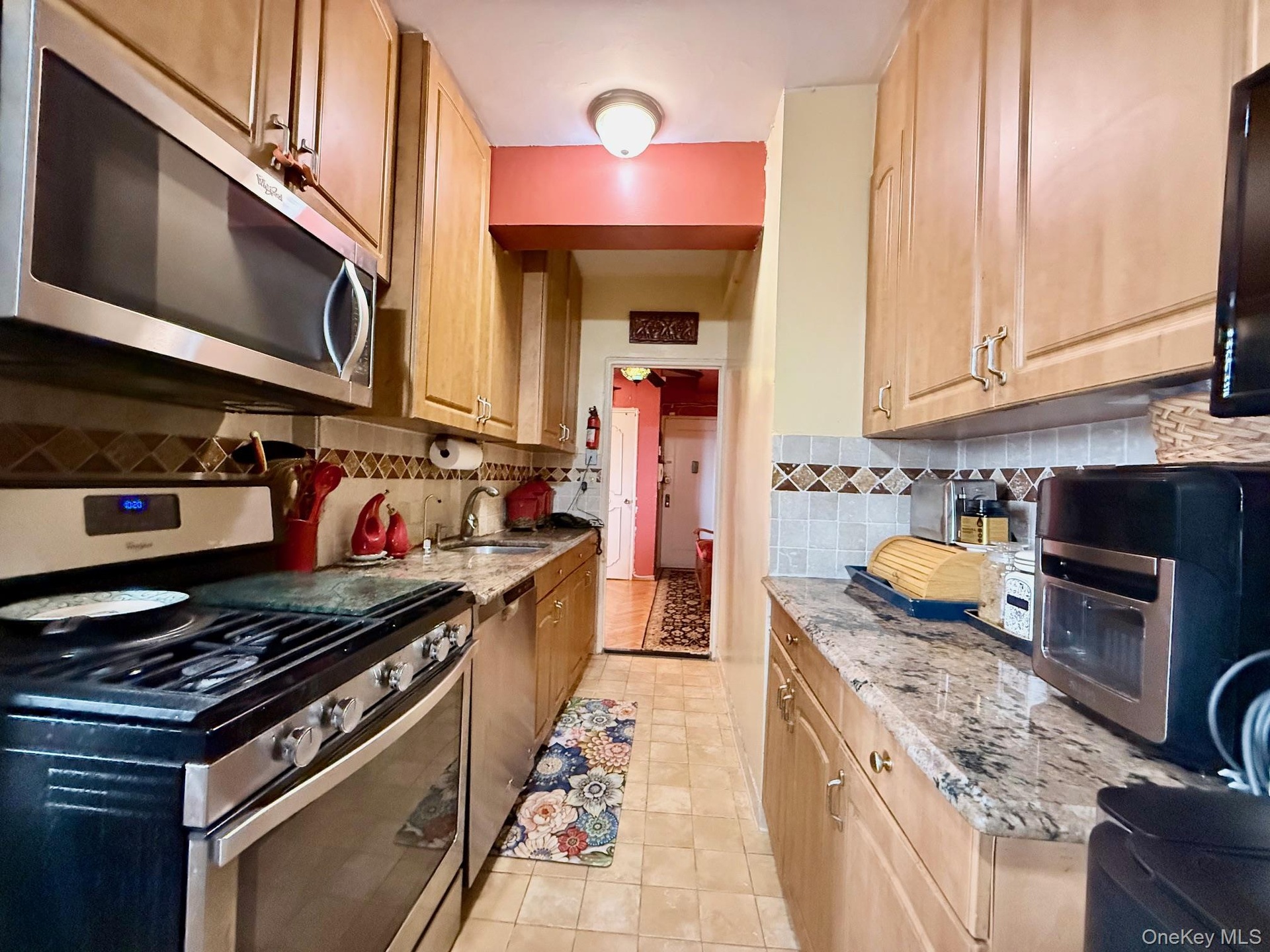 Well maintained kitchen, with light oak cabinets, granite countertop, tiled backsplash.