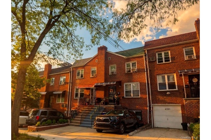Brick facade residence featuring multiple windows, a front porch with an awning, and a private driveway