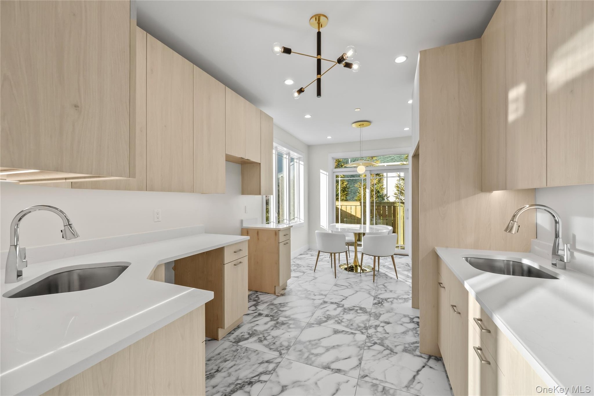 Kitchen with light brown cabinets, modern cabinets, light stone countertops, light marble finish flooring, and a chandelier