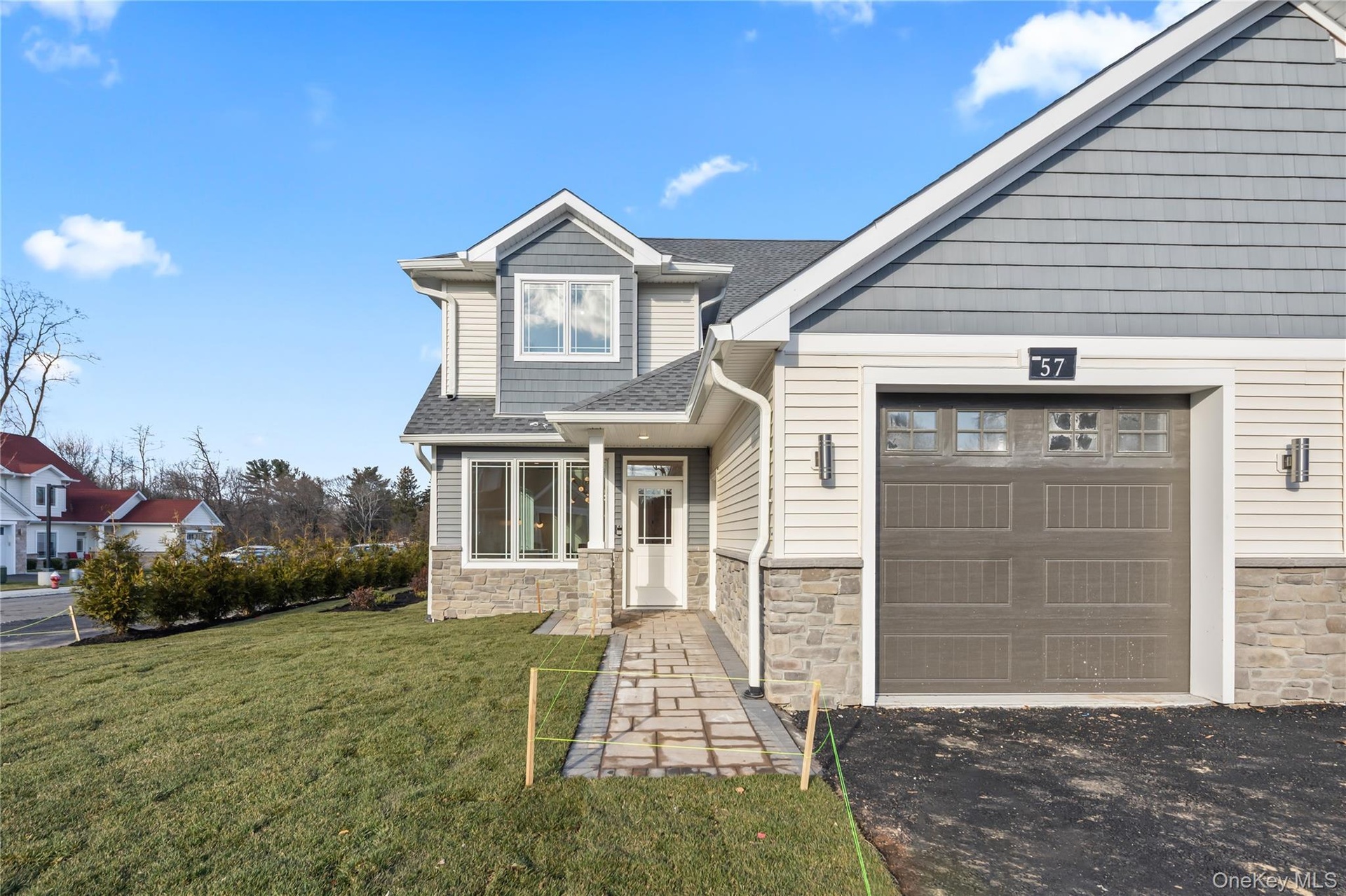 Craftsman house with stone siding, a front yard, and roof with shingles