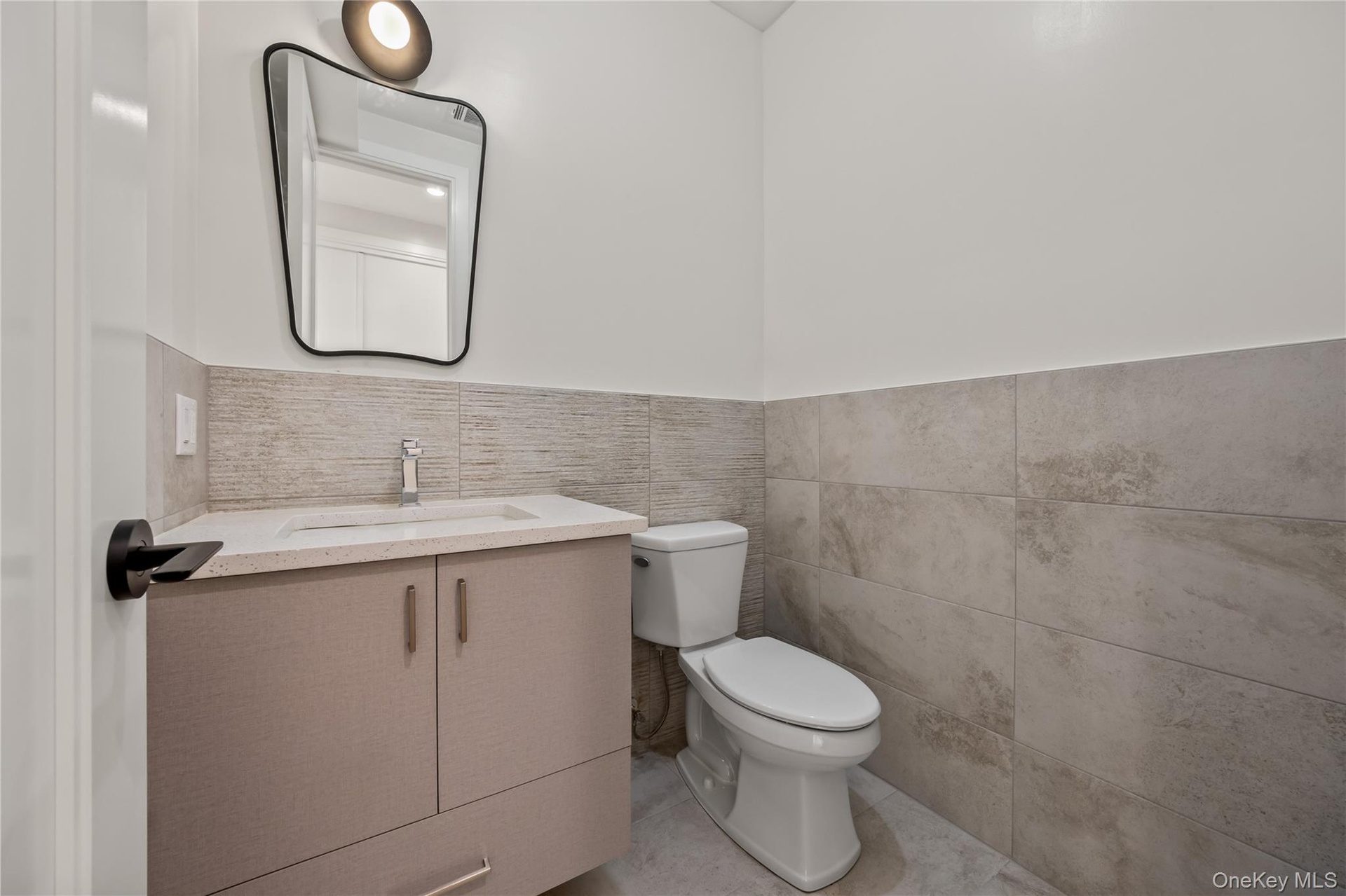 Bathroom with vanity, tile walls, light tile patterned floors, and a wainscoted wall