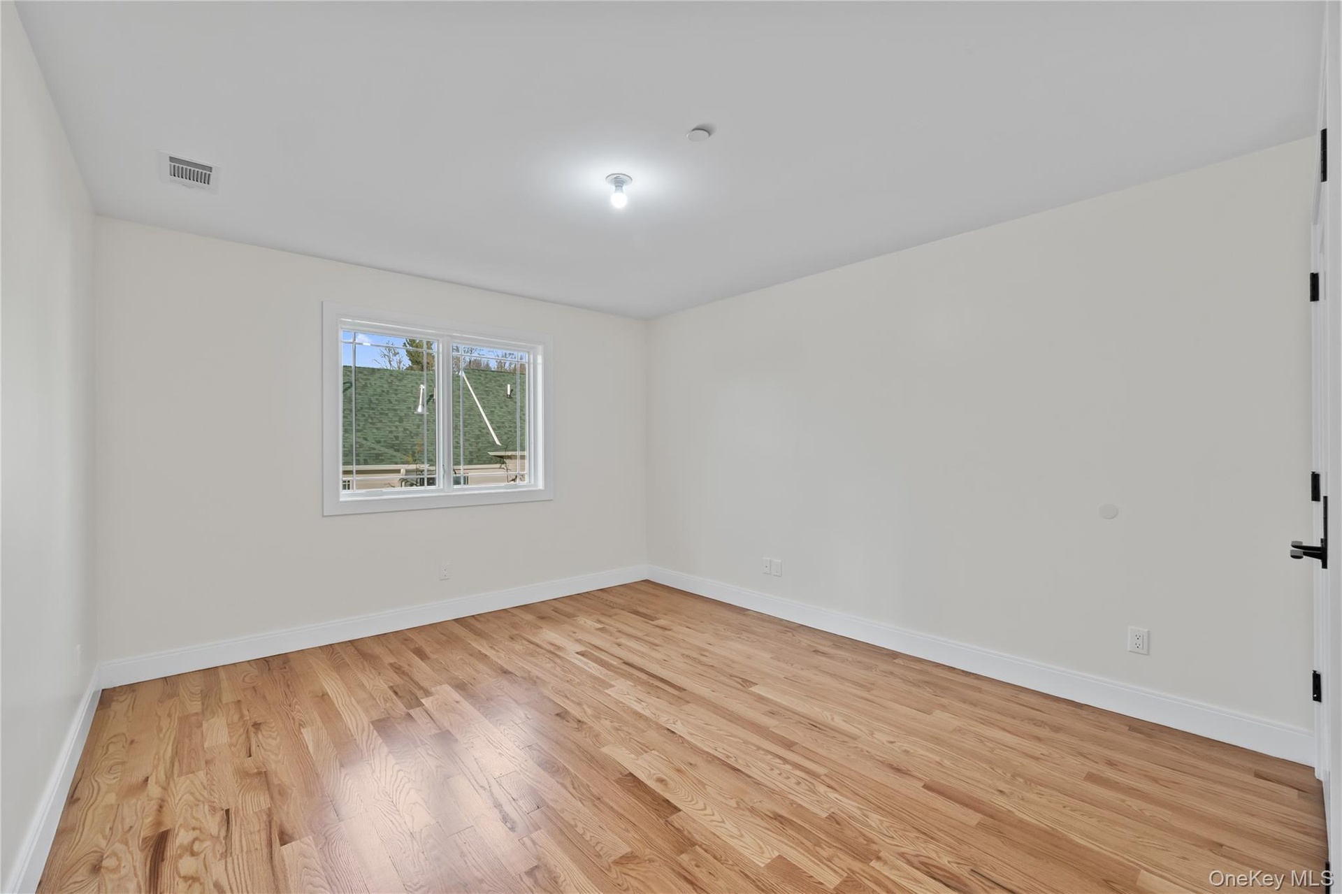 Unfurnished room featuring light wood finished floors and baseboards