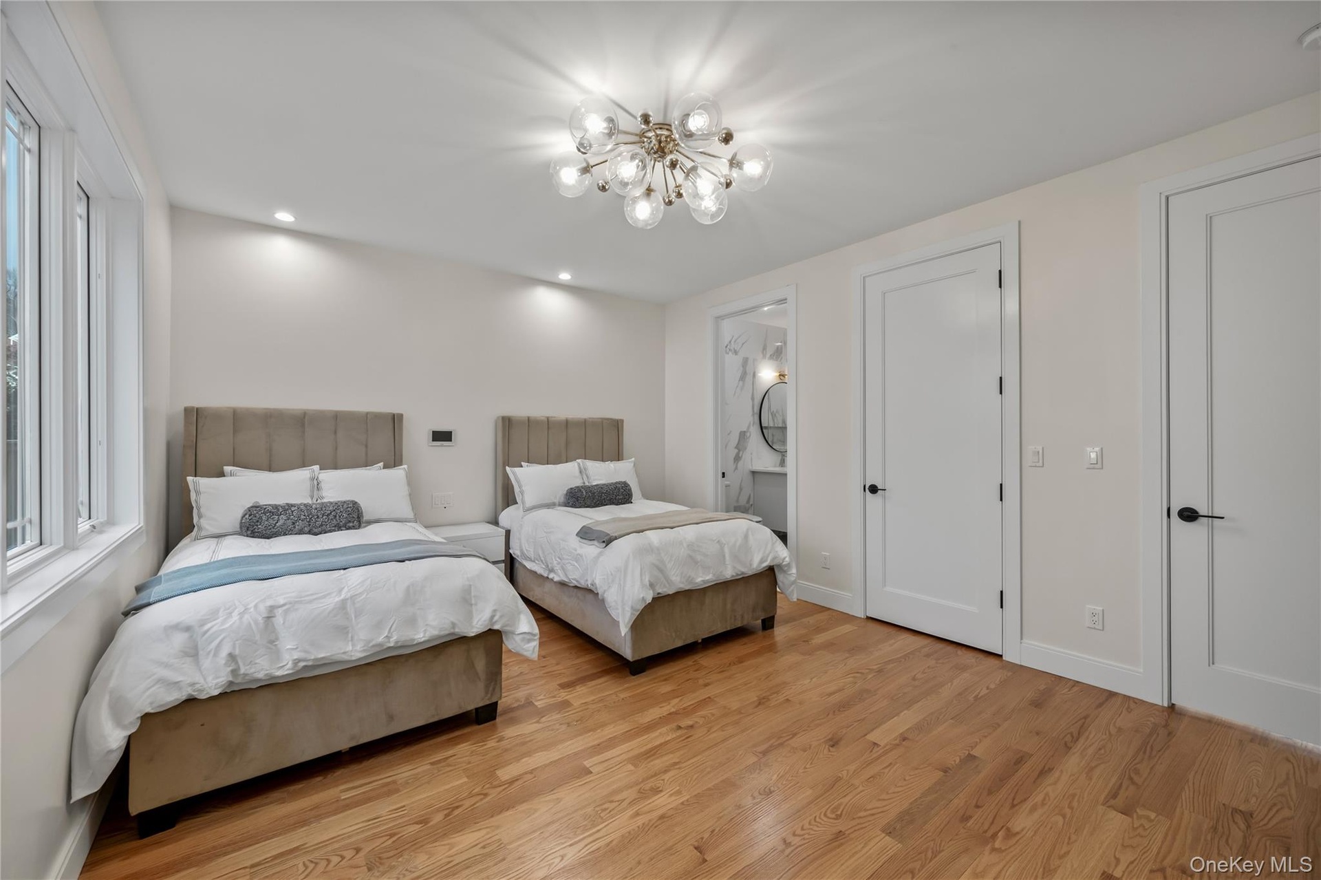 Bedroom with light wood-style flooring, recessed lighting, ensuite bathroom, and a chandelier