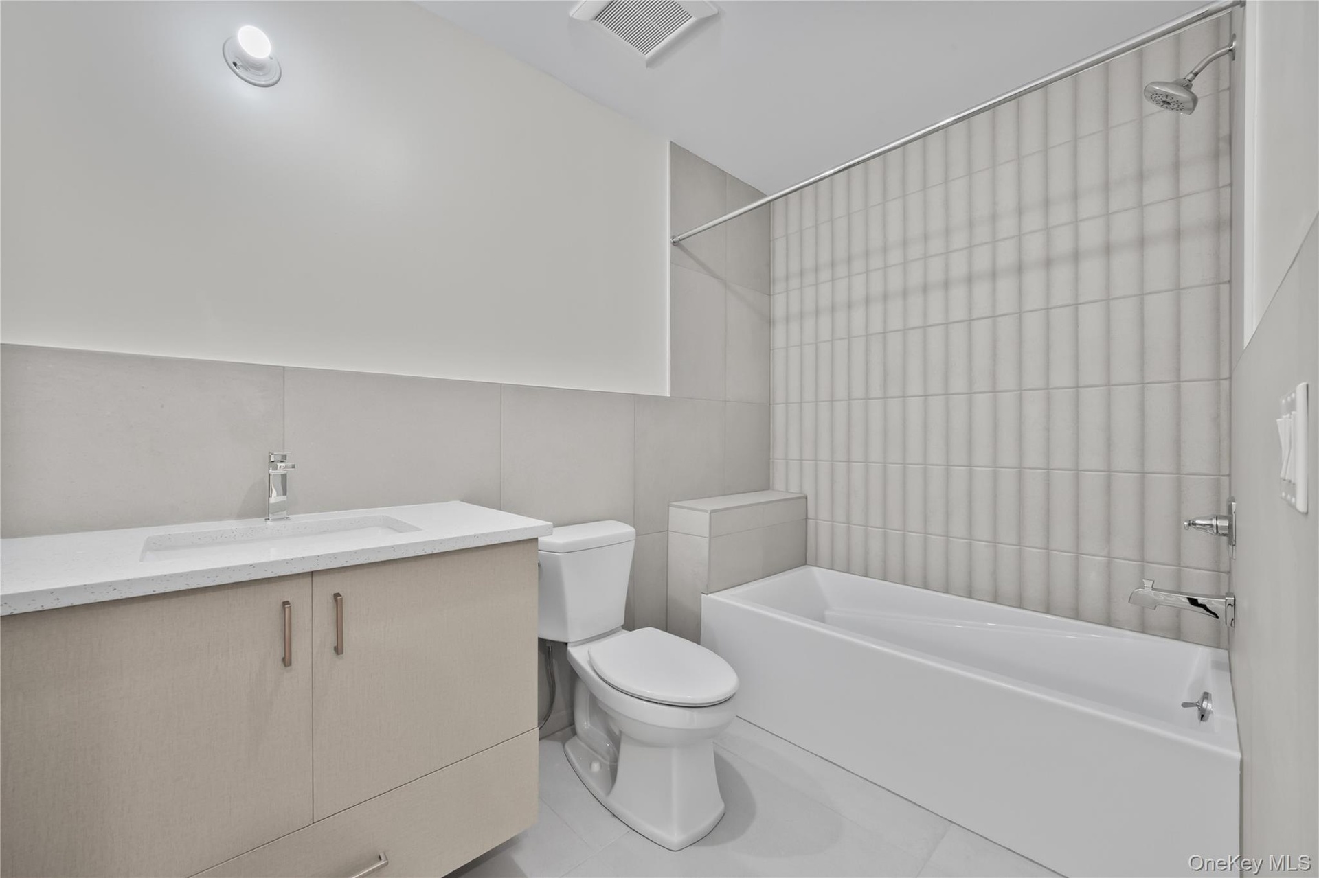 Bathroom featuring vanity, tile walls, tub / shower combination, and tile patterned floors