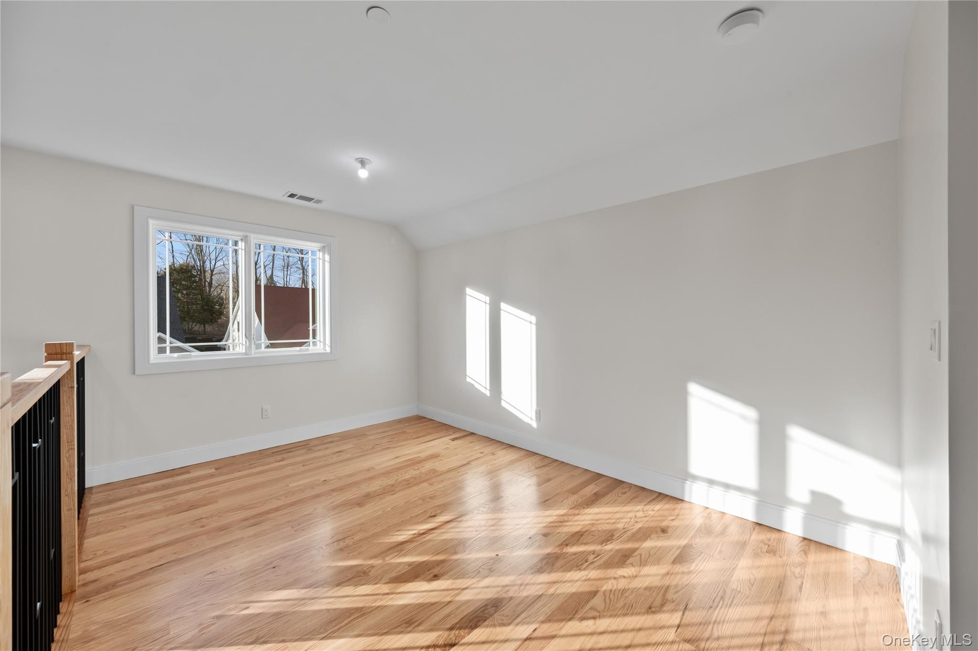 Empty room with vaulted ceiling and light wood-type flooring