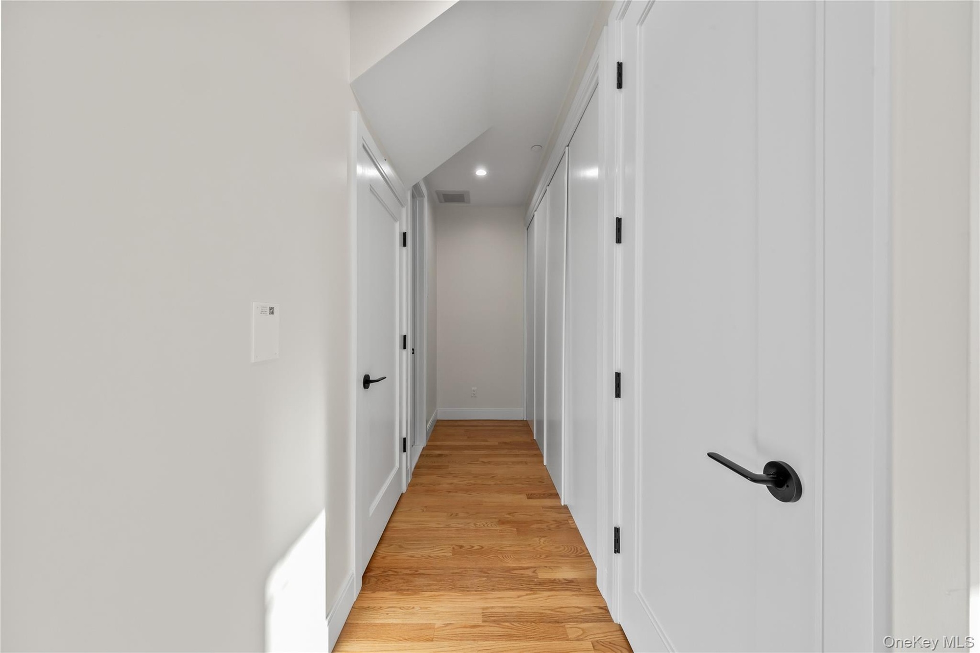 Hall with light wood-style floors and recessed lighting