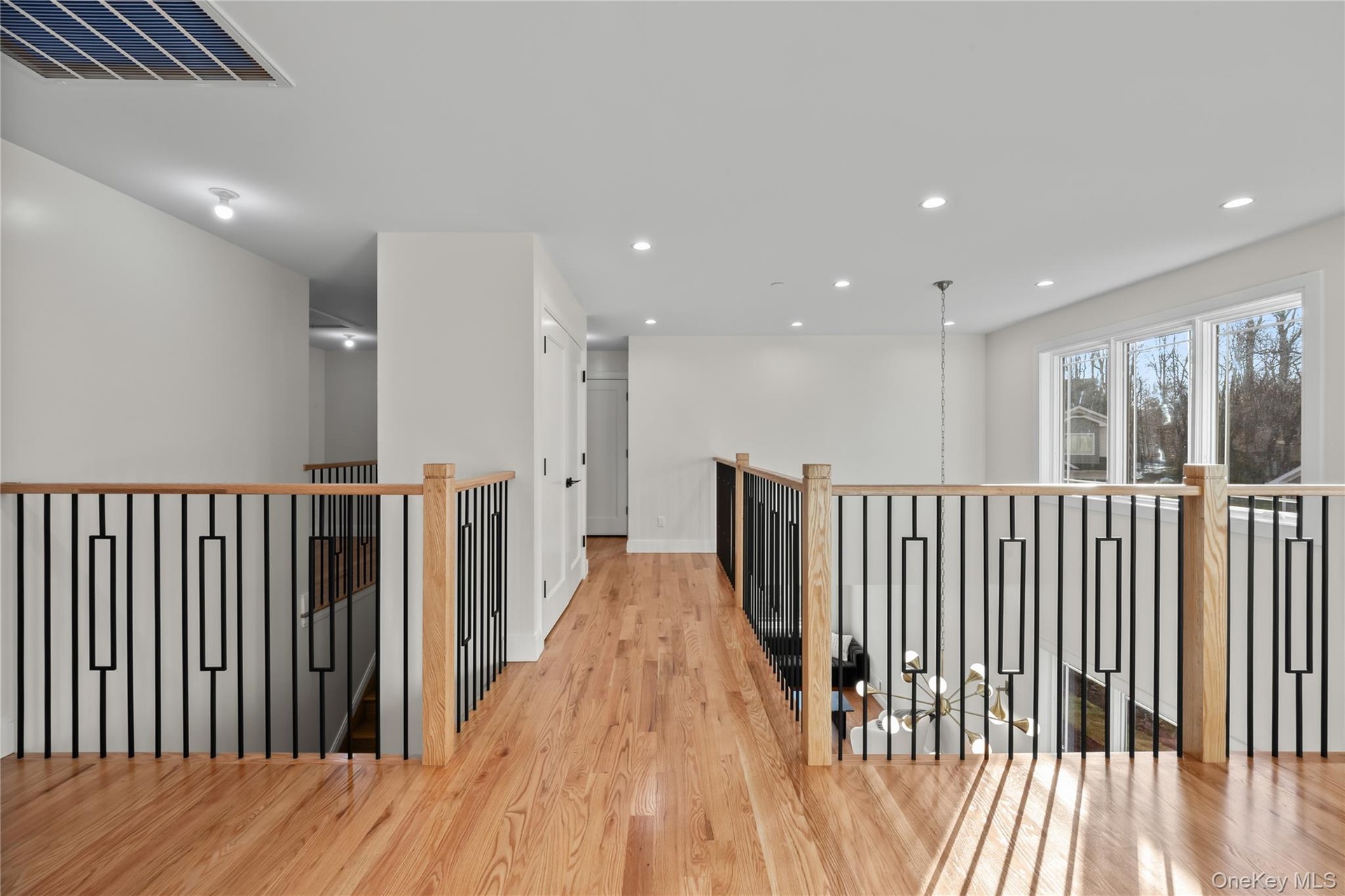 Corridor featuring light wood finished floors, an upstairs landing, and recessed lighting