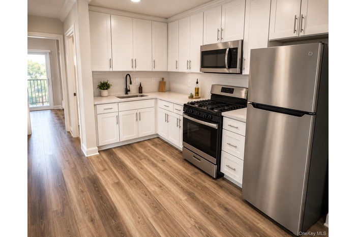 Modern kitchen featuring white shaker cabinetry, stainless steel appliances, light-toned countertops, a subway tile backsplash, and wood-finish floori