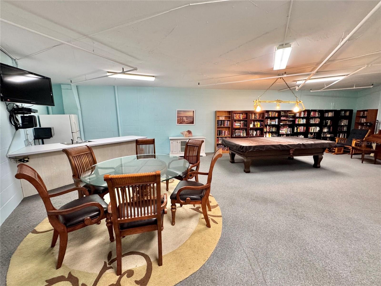 ACTIVITIES ROOM / Game room with billiard table, TV, dining table for 6, couch, piano, library and refrigerator.